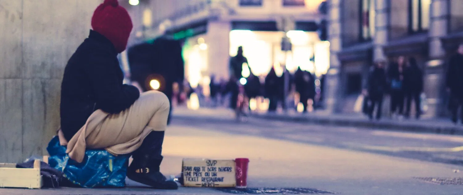 person sitting beside building looking straight to the street at golden hour
