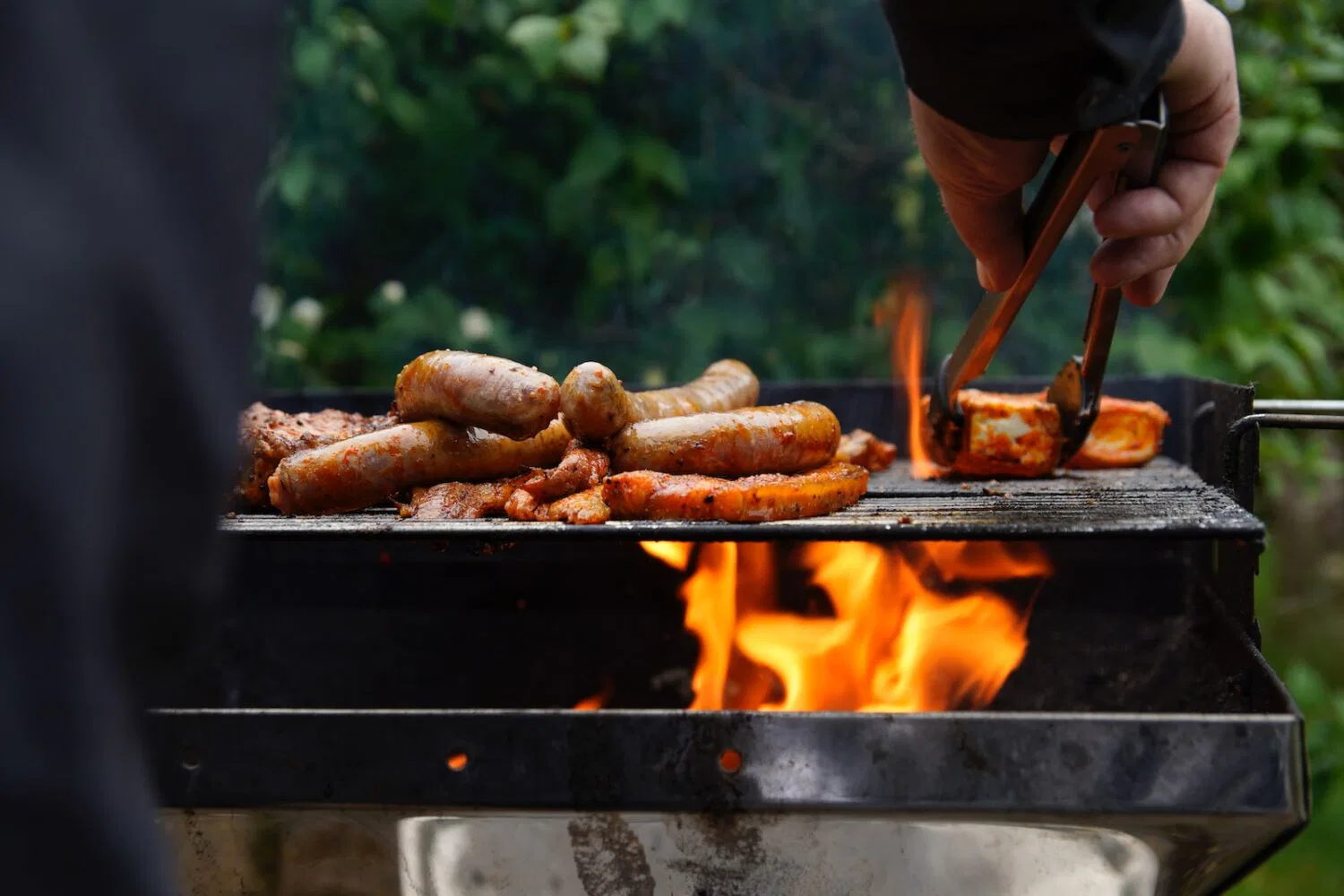 person holding a stick with meat on a grill