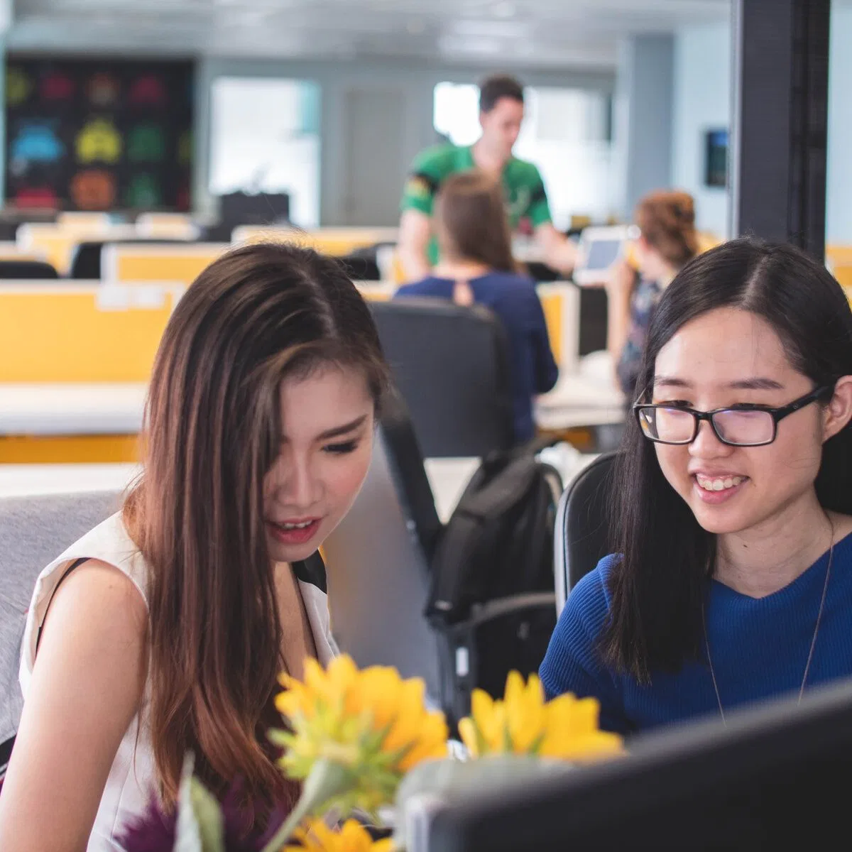 two women smiling in front of computer monitor