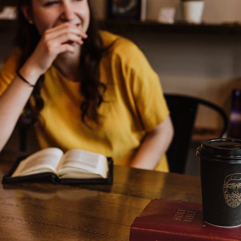 woman siting on chair near on holy bible