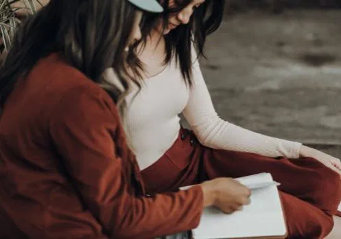 woman in white tank top and orange jacket holding white printer paper