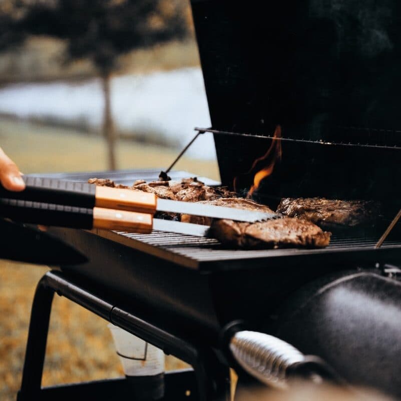 person grilling meat outdoors
