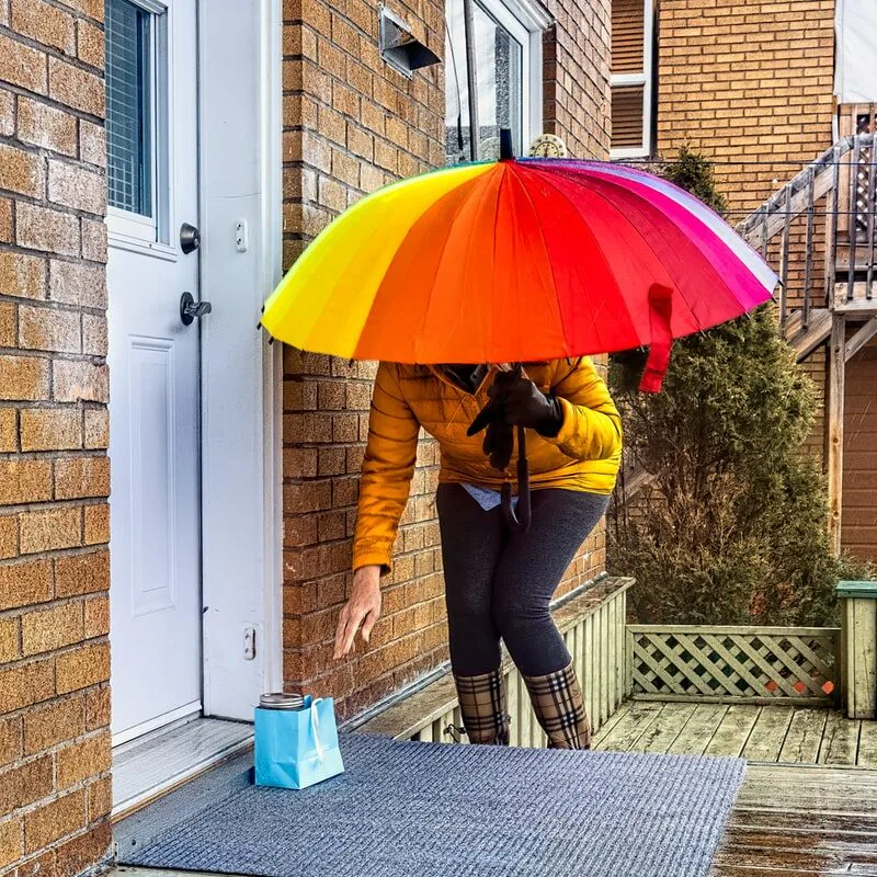 woman in brown jacket and blue denim jeans holding red umbrella